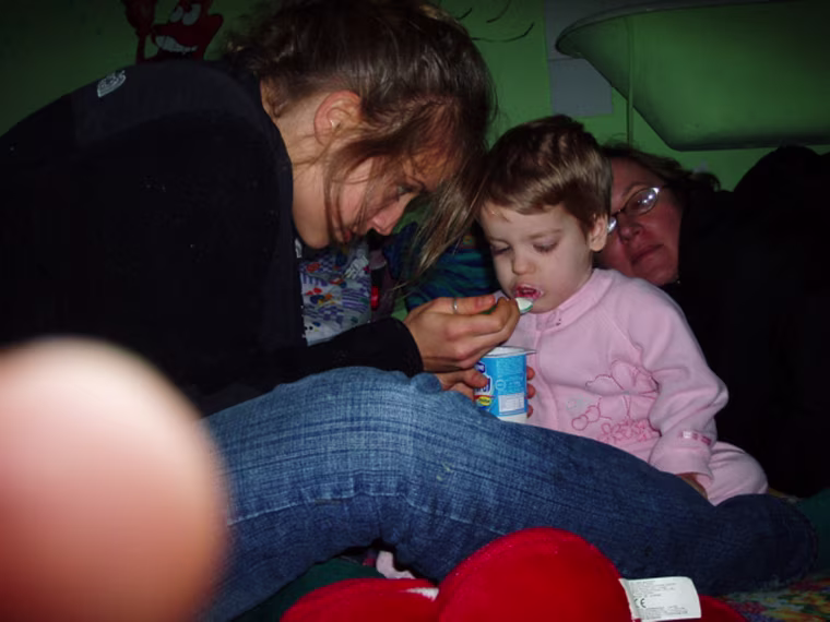 In this photo released by Global Volunteers, Emma Fisher feeds a girl named Ana-Maria while volunteering at Tutova Hospital's Failure to Thrive Clinic  in Tutova, Romania,January 2006. AP Photo/Lilly Fisher)